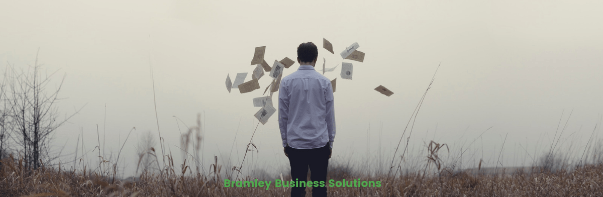 how to organise files. A man standing with papers flying all around him.