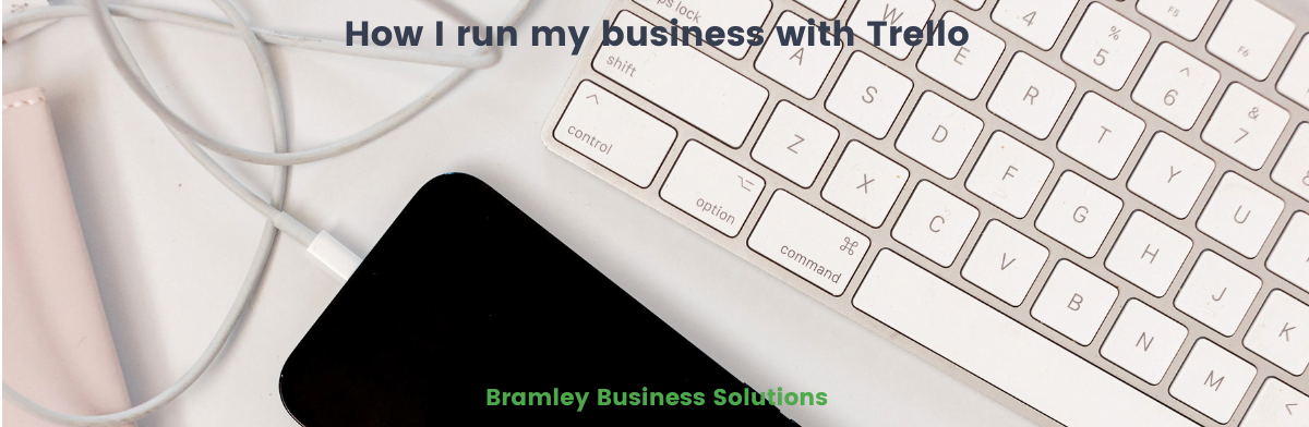 keyboard, cable and phone on a desk with title of blog overlaid How I run my business with Trello